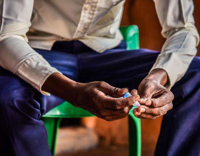 A diabetic refugee from Somalia sits in Dagahaley camp, Kenya, holding his insulin.
