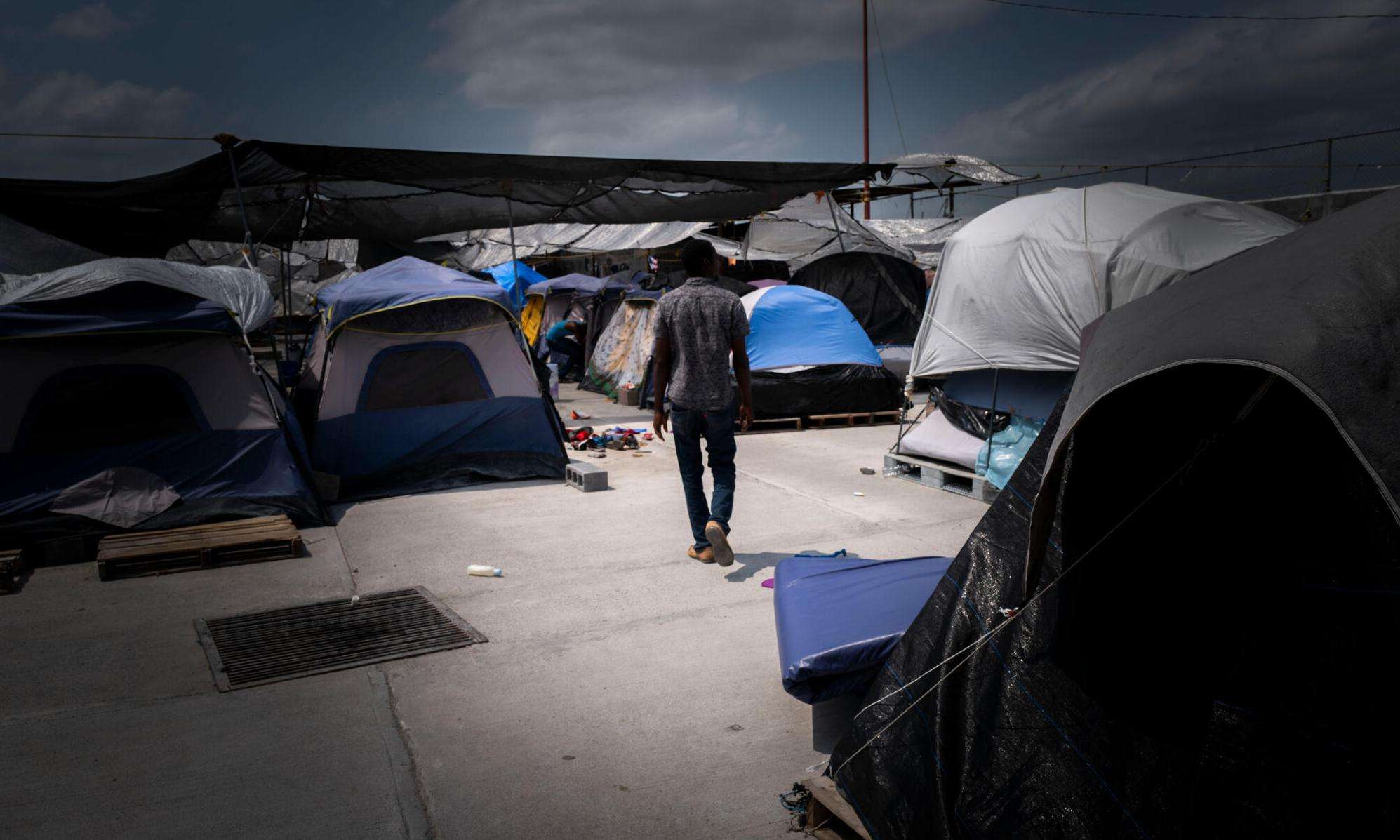 A man walks through the "Senda de Vida" migrant shelter in Reynosa, Mexico, at the US southern border. Hundreds of families relocated to this shelter in May 2022 after a camp that had formed in a public plaza was evacuated and cleared away. At the time, two thousand people were living in the camp, including hundreds of children.