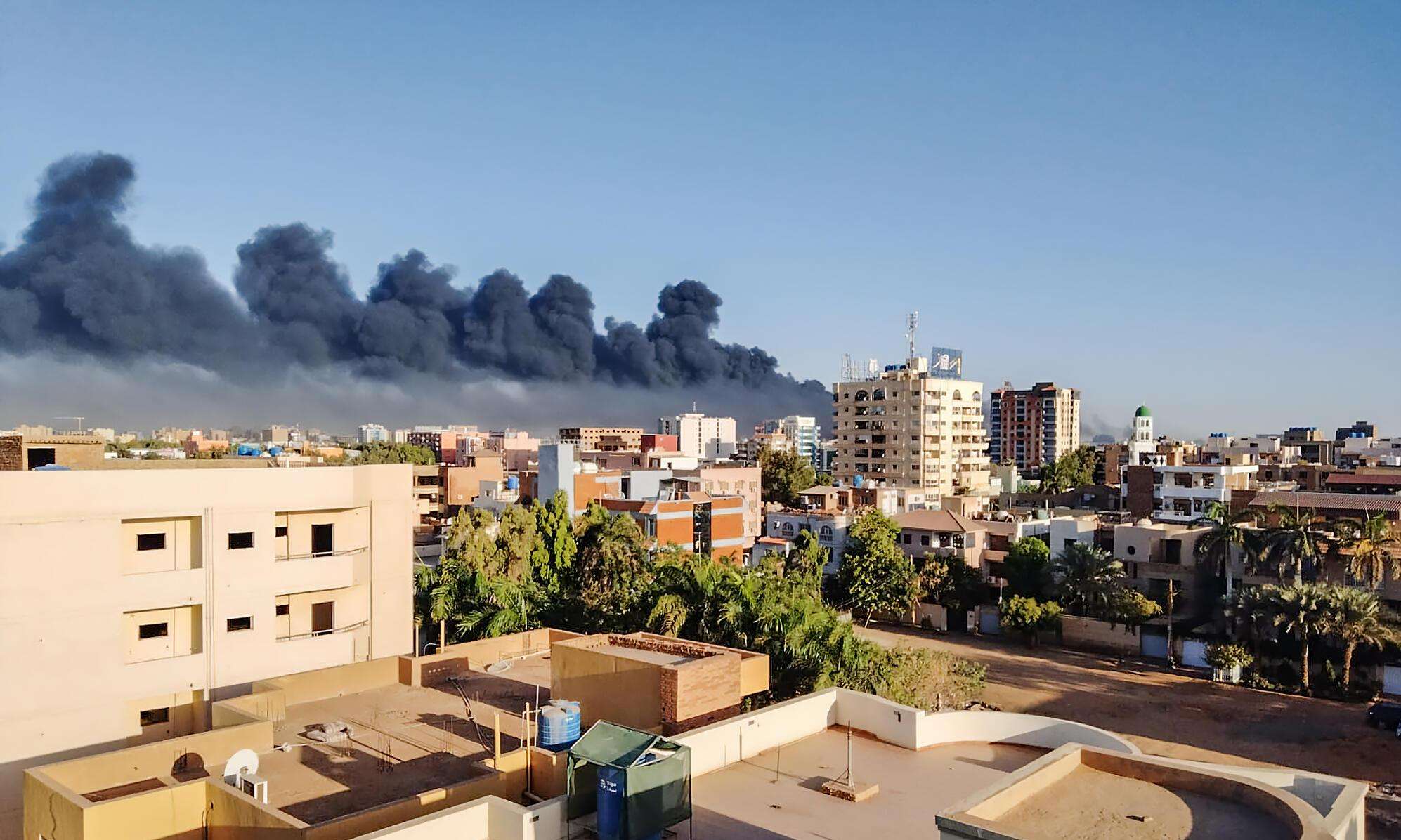 A scene of the city of Khartoum and a billowing fire in the background.