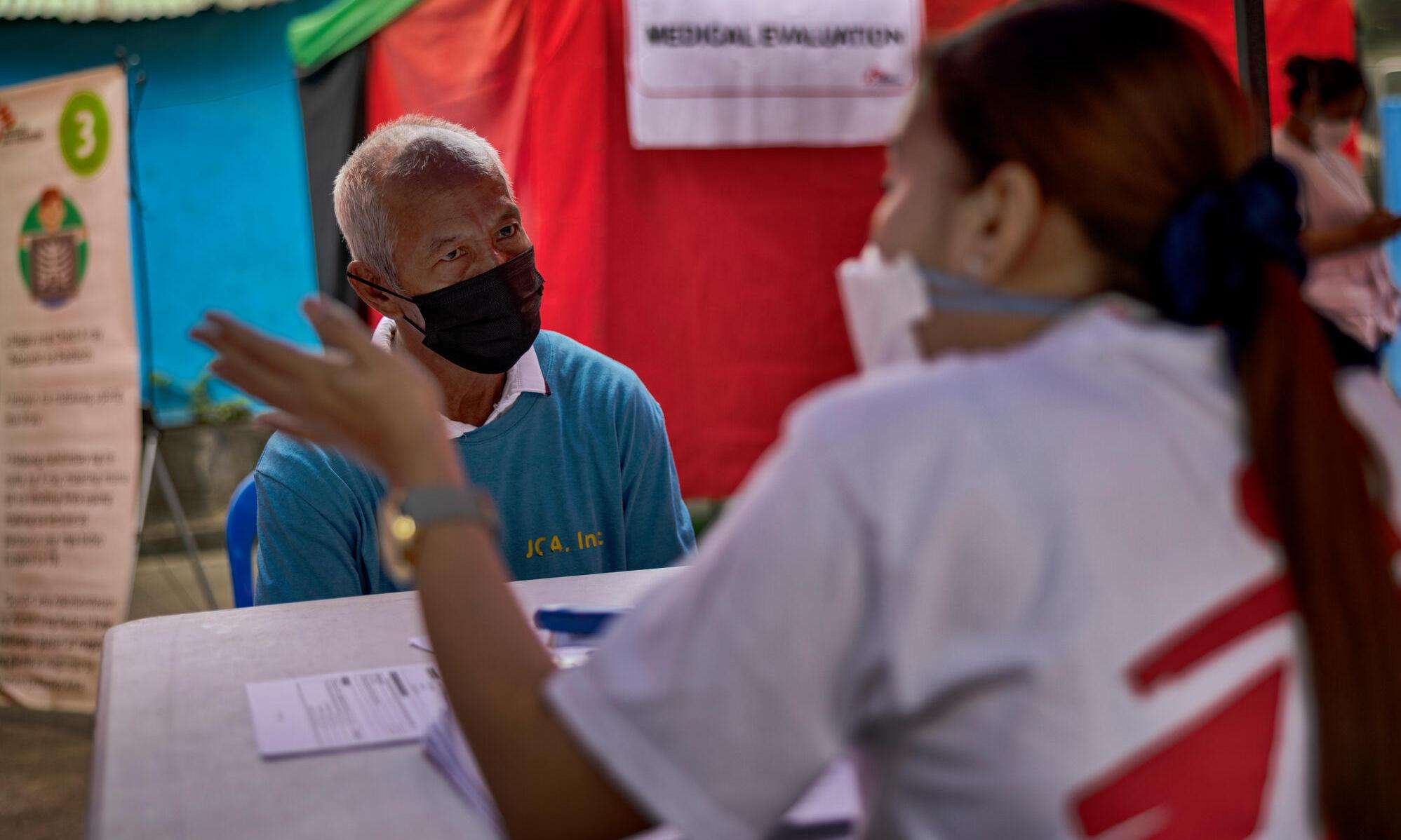 A patient sits at a table in front of an MSF staff member for a free X-ray at an MSF tuberculosis (TB) screening sites in Manila.