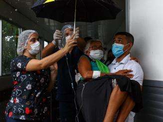 Medical team holding a woman outside and under an umbrella