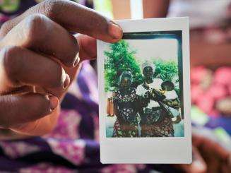 A woman holds a polaroid photo of a family in Mozambique.