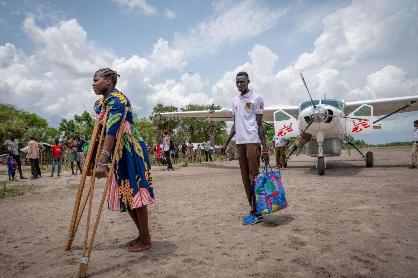Woman on crutches transferred by plane for medical treatment by MSF in South Sudan.