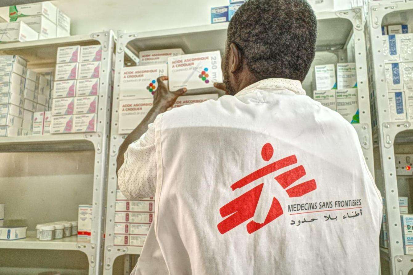 An MSF staff member in Sudan looks at medical supplies on a shelf at Umdawanban hospital near Khartoum