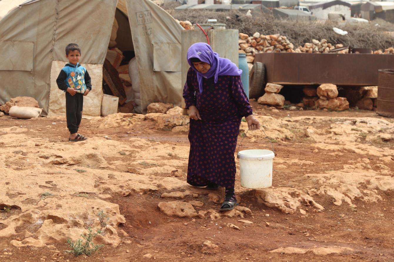 A woman fetches water with a bucket at a camp for displaced people in Idlib province, Syria.