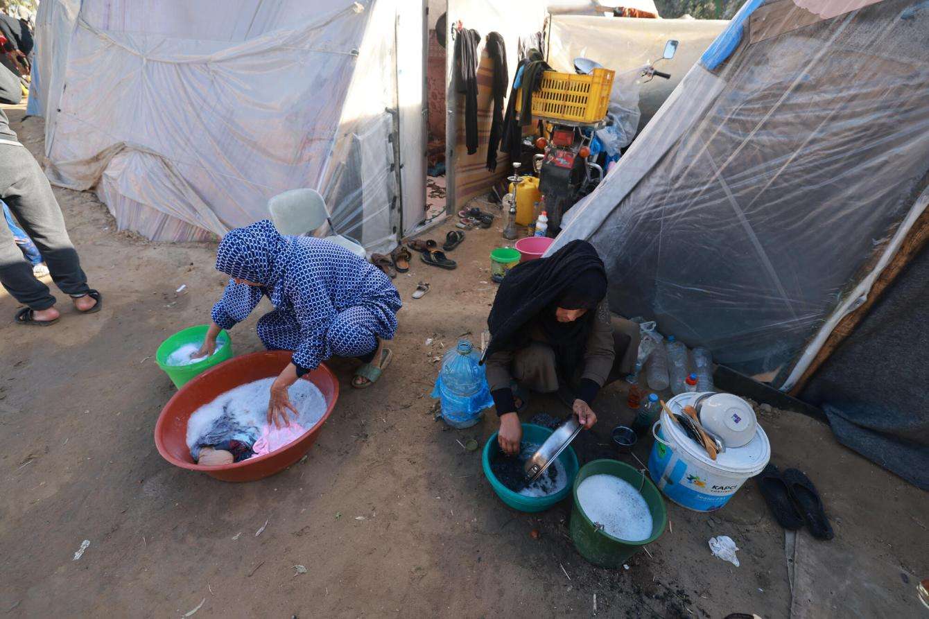 Displaced Palestinian women wash clothes and dishes in buckets outside their tents in the southern Gaza town of Rafah’s Al-Shaboura neighborhood, on January 27, 2024.
