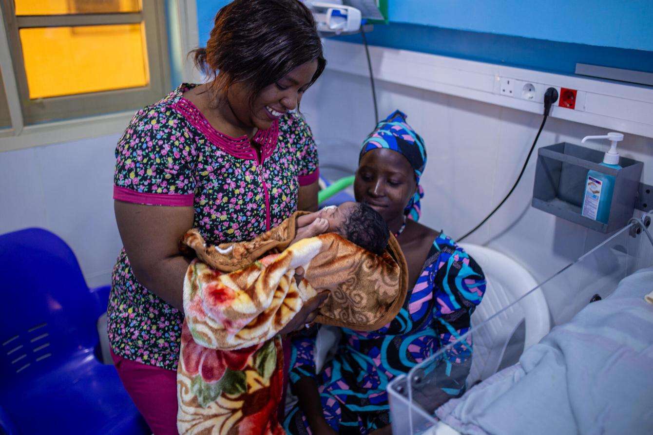 A nurse holds a newborn baby beside the baby's mother at Jahun Hospital in Nigeria.