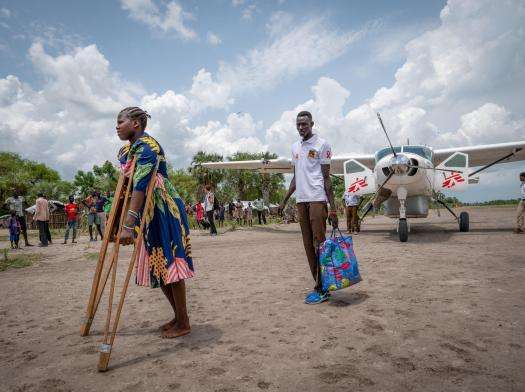 Woman on crutches transferred by plane for medical treatment by MSF in South Sudan.