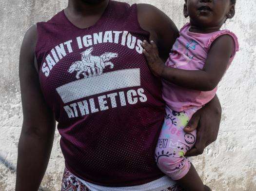 A woman in a T-shirt holding a child in Mozambique.