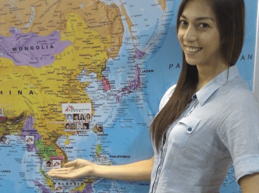 Julie Papango, MSF clinical laboratory scientist stands in front of a world map