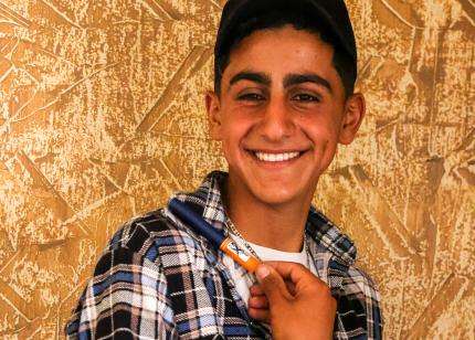 A young boy in Lebanon smiles holding his insulin pen for diabetes.