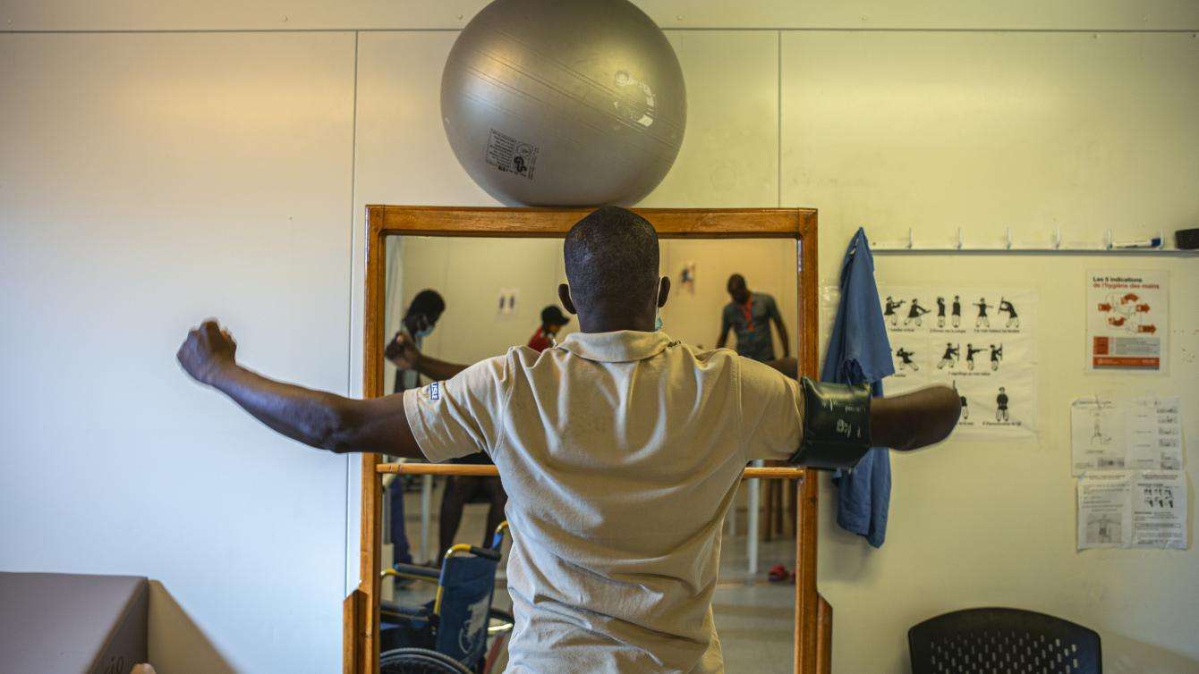 Wilfrid balancing an exercise ball on his head, during his physiotherapy session at MSF Tabarre’s hospital.