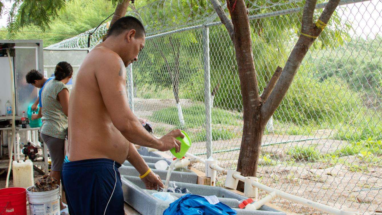 An asylum seeker washes his clothes at one of the water points in the camp