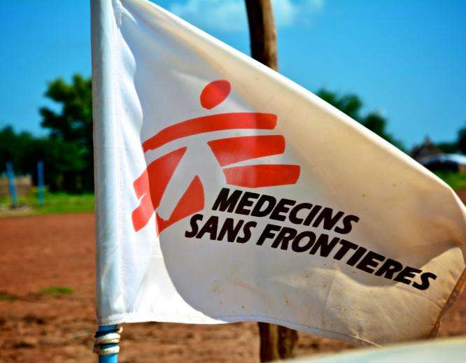 White flag with red logo of Doctors Without Borders/Médecins Sans Frontières (MSF) against sunny blue sky