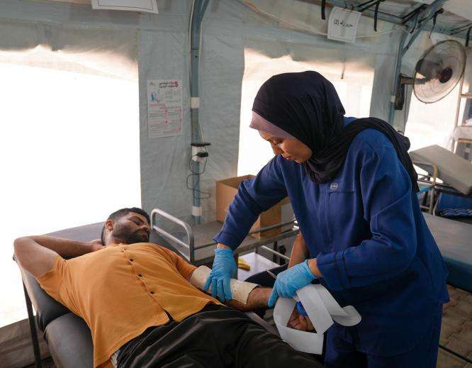 A physiotherapist adjusts the fit of a patient's splint at Al-Zawayda field hospital.