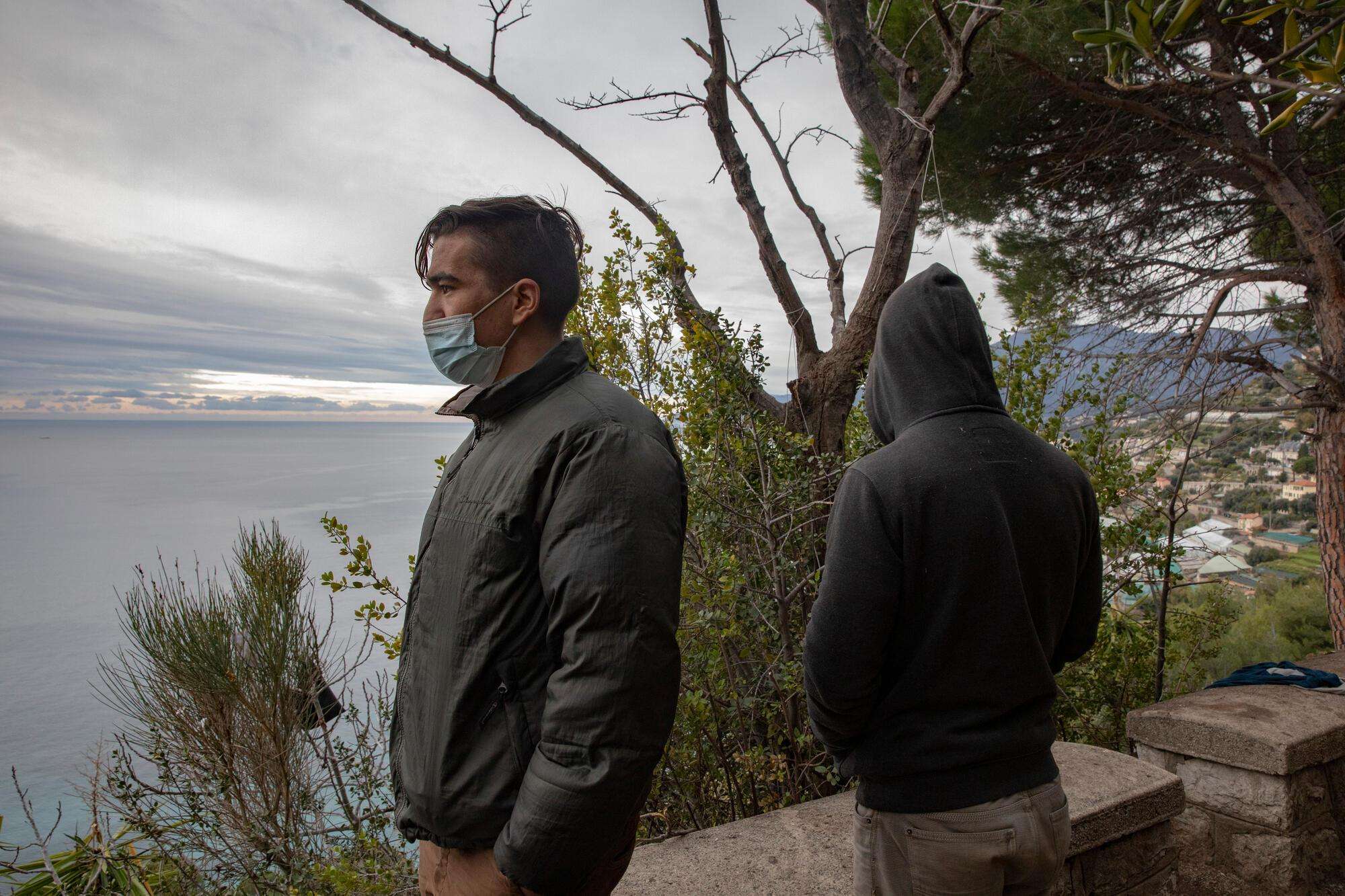 Two refugees look out over the Mediterranean Sea above Ventimiglia.