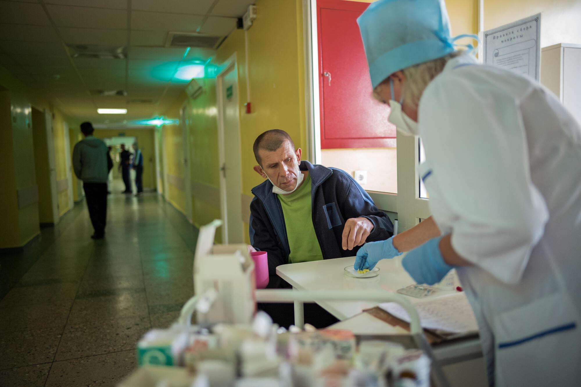 A patient at the TB institute takes his medications in front of a nurse. 
