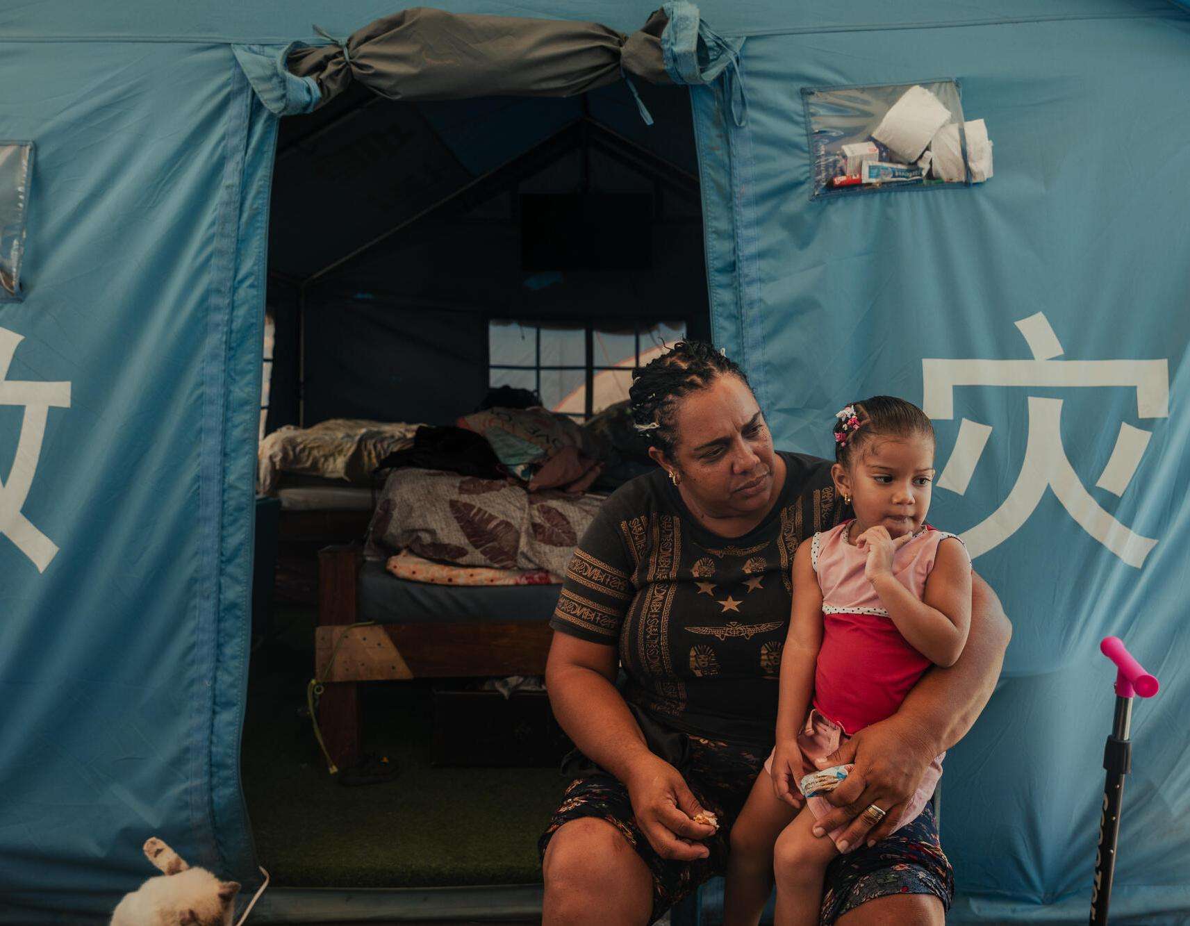 A displaced woman and child in front of a tent in Venezuela.