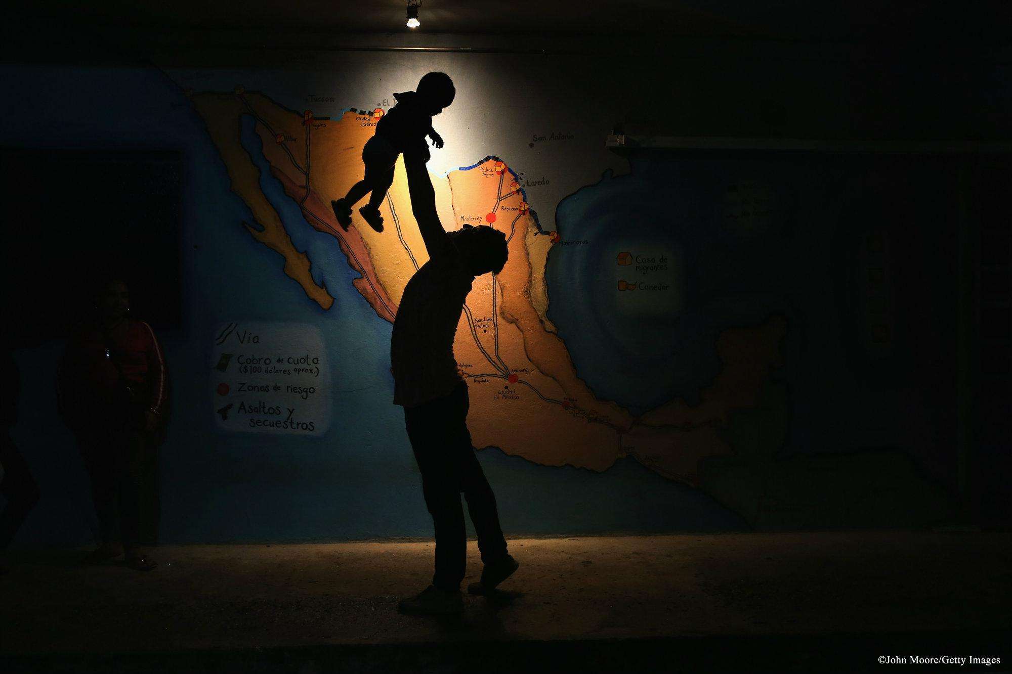 A Honduran man holds a young child at La 72 shelter in Mexico