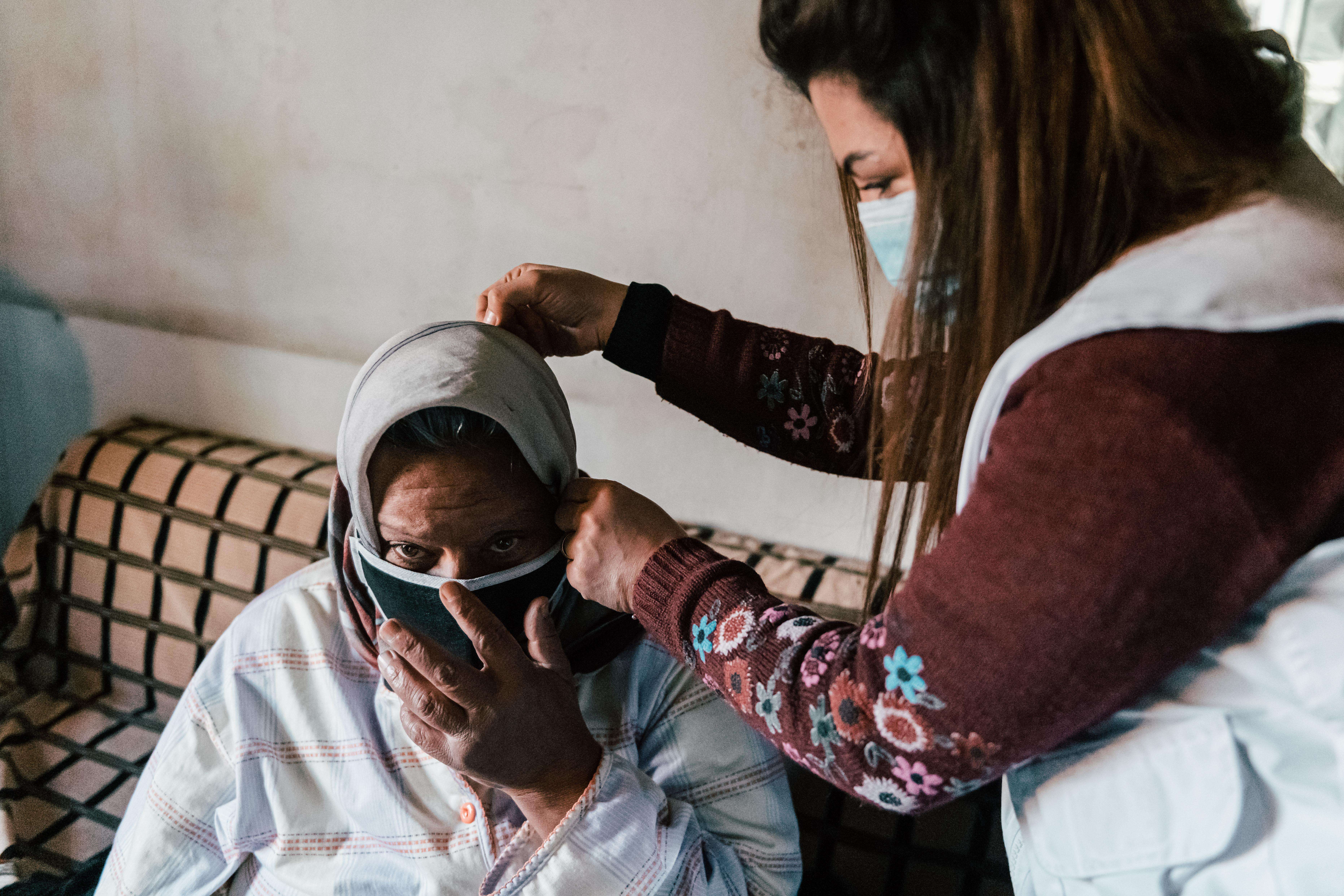 Medic putting a mask on a woman in her home