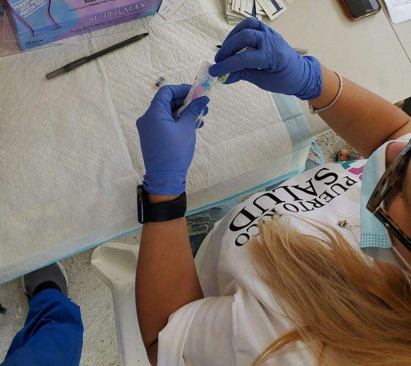A member of local health organization, Puerto Rico Salud, prepares a dose of the COVID-19 vaccine.