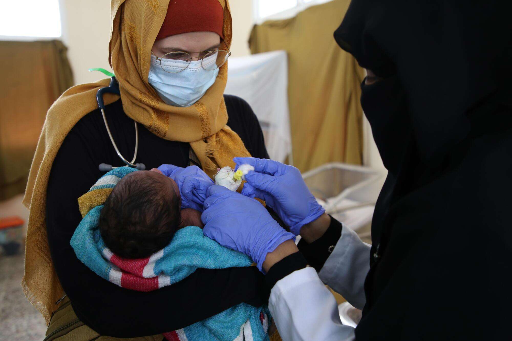 Nurse in northwestern Yemen holding a sick infant in her arms