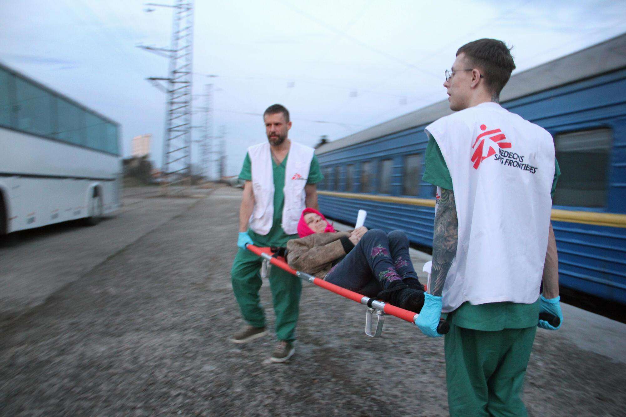 MSF staff members transport a patient from our medical train after its arrival in Lviv from Kramatorsk on April 7, 2022. The train evacuates patients in need of higher levels of care from hospitals close to the front lines.