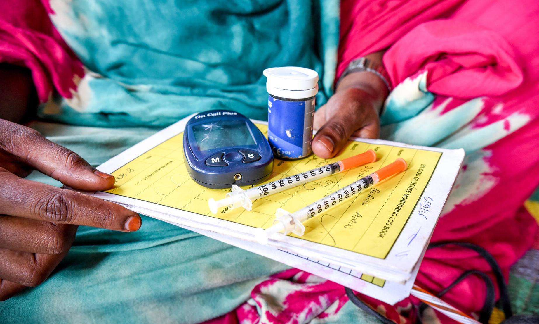 A woman holds her diabetes medications including insulin pens.
