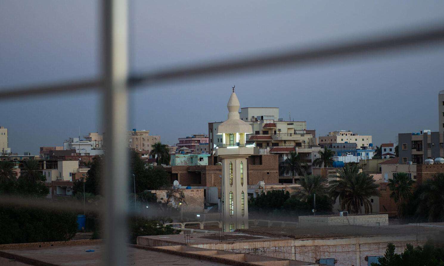 View of an urban landscape in Sudan through the bars of a fence.