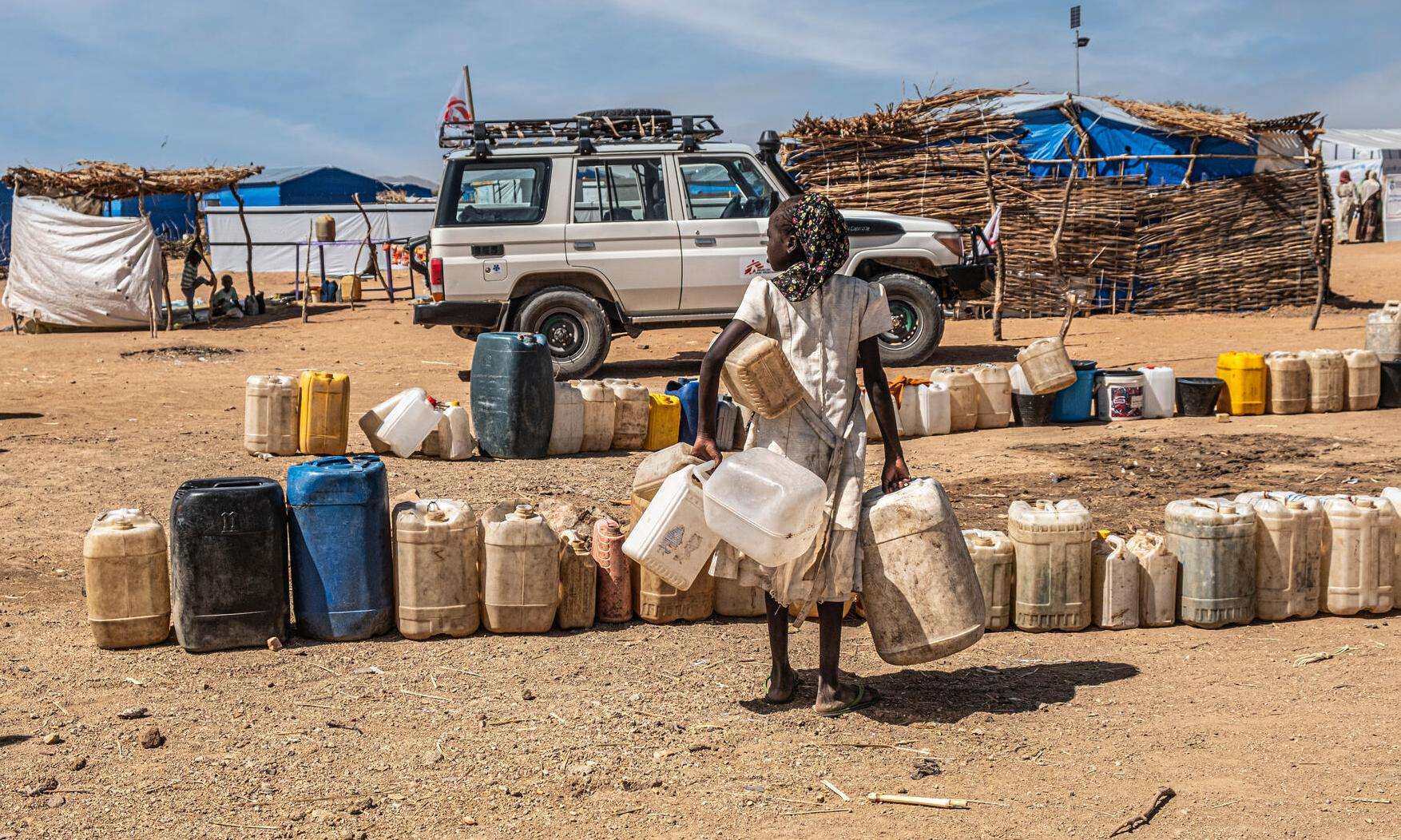 A woman holding jerry cans of water at a water distribution point in eastern Chad.