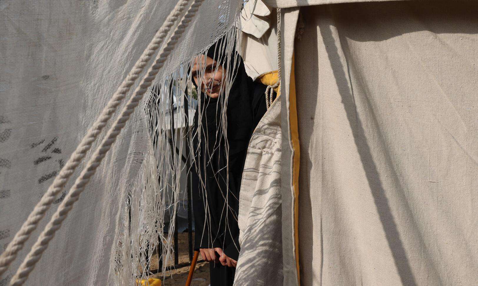 A Palestinian woman seen through the folds of a makeshift tent in the Rafah area, southern Gaza.