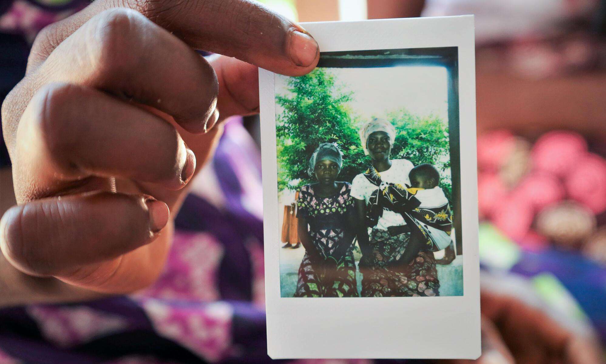A woman holds a polaroid photo of a family in Mozambique.