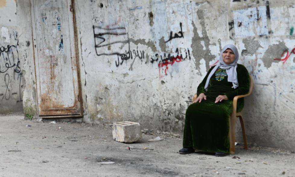 A Palestinian woman sitting beside a wall in the West Bank.