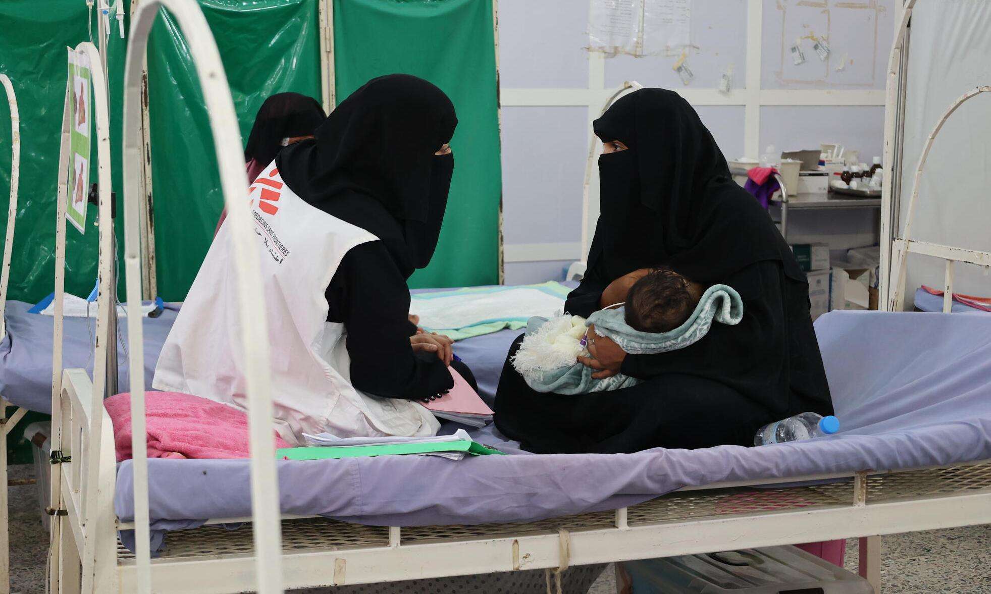 A social worker speaks with a mother in a hospital in Yemen. 