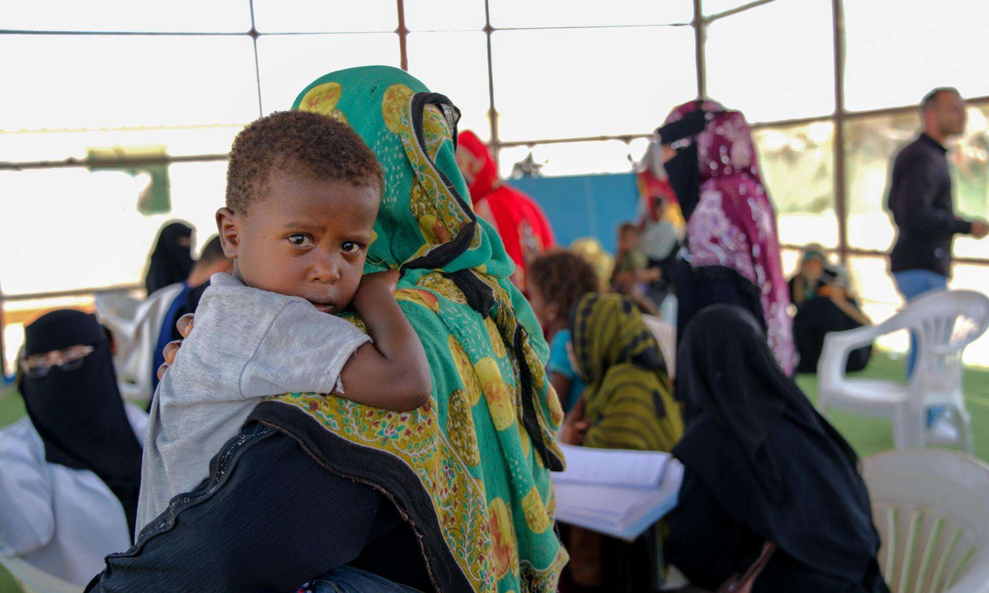 A mother holds a child in a hospital lobby in Yemen. 
