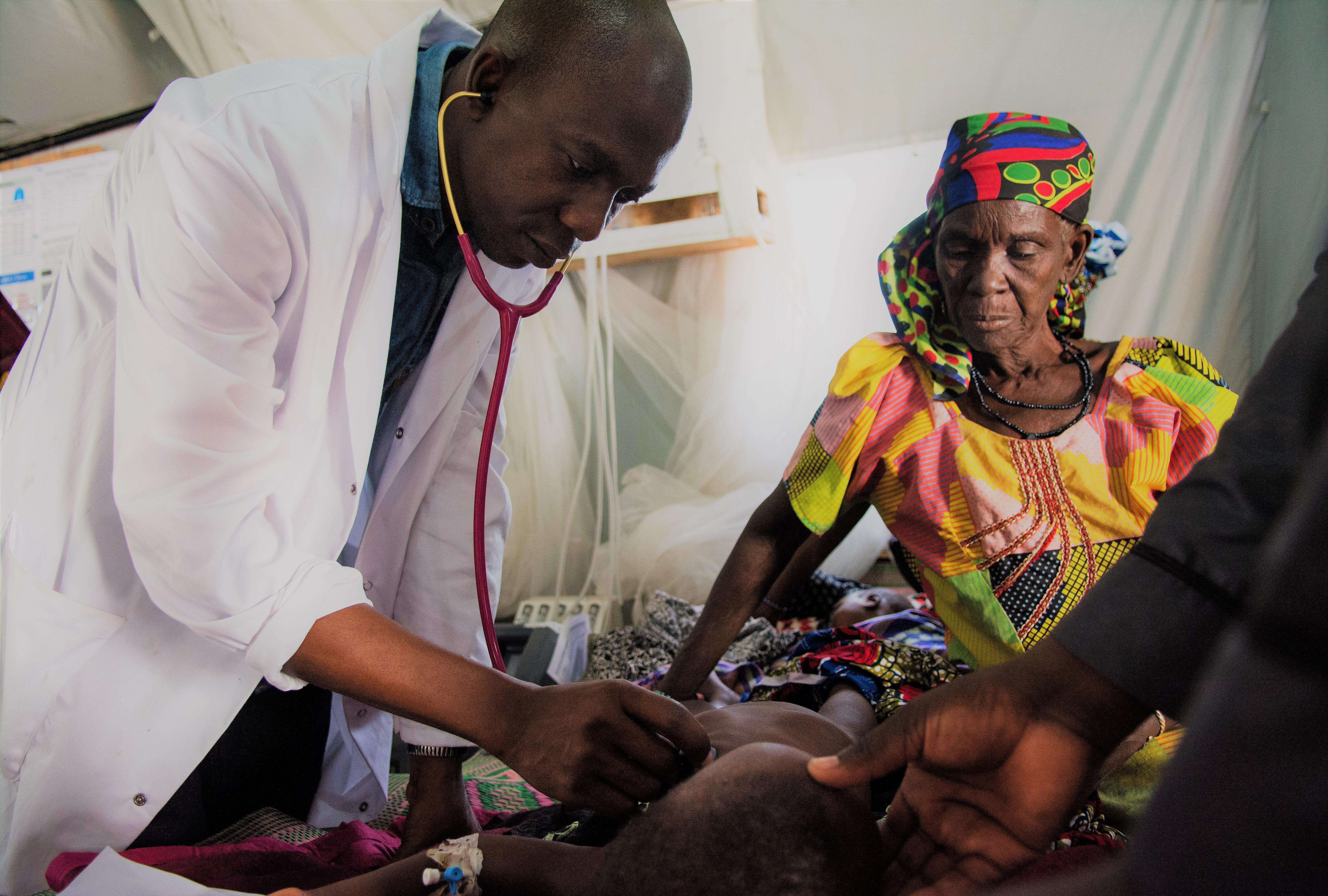 A physician providing care to a sick child at MSF's temporary hospital at Dungass, in the Magaria area