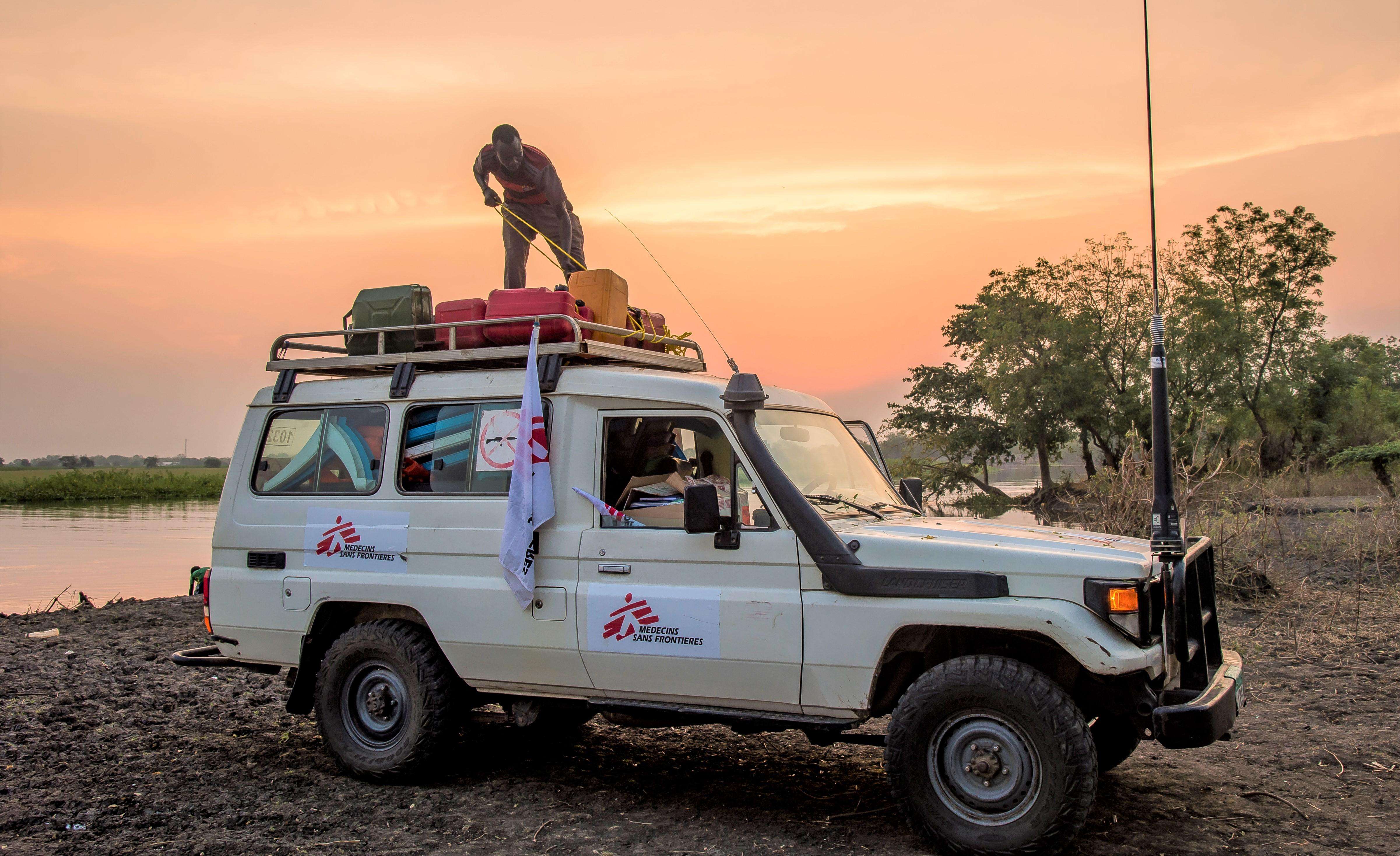 In a remote area of South Sudan, an MSF logistician, attaches to the roof of a 4x4, the equipment that a mobile clinic team has just brought back after a day of mobile boat clinics.