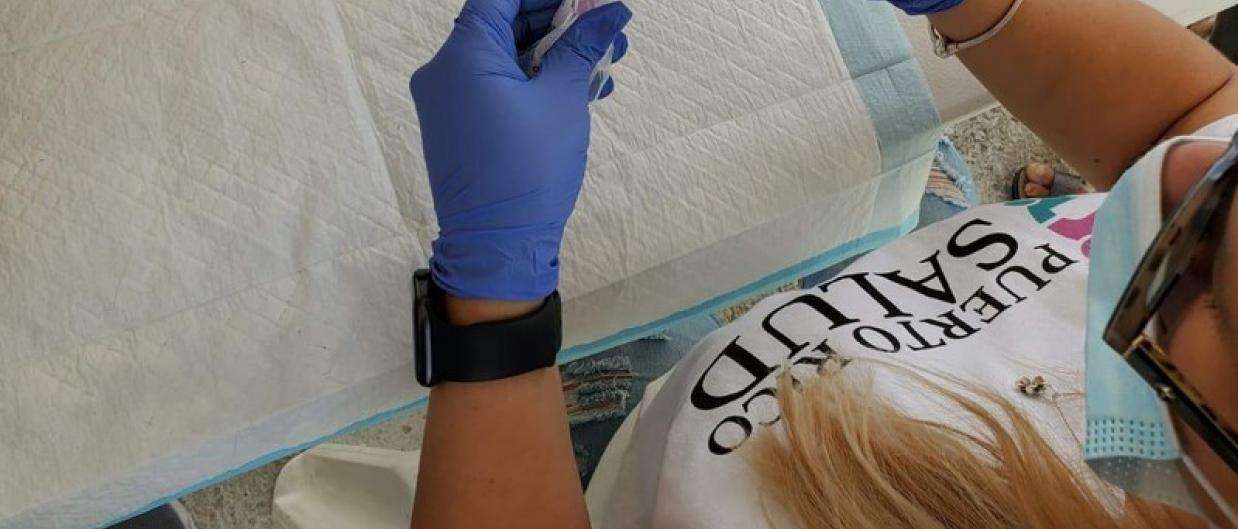 A member of local health organization, Puerto Rico Salud, prepares a dose of the COVID-19 vaccine.