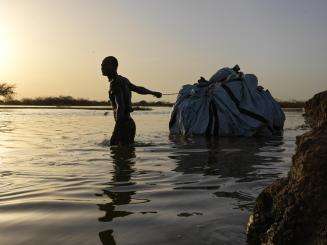 A man carries belongings through flood waters