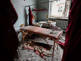 A hospital bed in Ukraine covered in broken glass and debris from shelling.