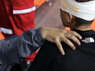 A man puts his hand on his injured friend's shoulder in support.