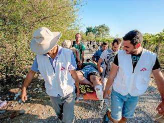 MSF aid workers transport a patient on a stretcher together with his friends. A refugee from Iraq, is suffering with severe foot pain, following a fall on arrival onto one of the Greek islands. 