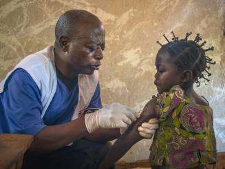 MSF staff member gives a measles vaccination to a young girl