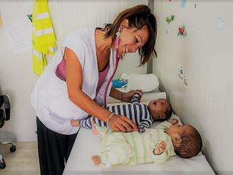 MSF's pediatrician, Carola Buscemi, examines a pair of 3 month old twins from Afghanistan.