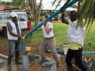 Watsan Technician Agbor John Assam (left), Watsan Manager Rosana Arrieche (centre) and Watsan Agent Igbozulike Emmanuel Chukwuka (right) install a hand-operated water pump at the Abgokim clinic. 