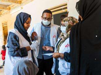Three MSF medical staff discuss patients at a mobile clinic in Wad Madani, Sudan.