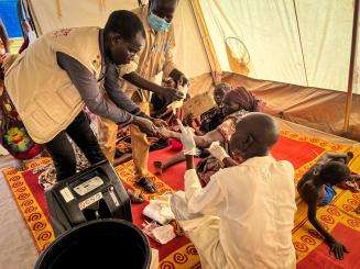 An MSF aid worker provides medical care to Sudanese refugee in tent hospital in Chad