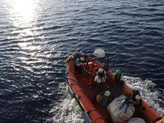 MSF search and rescue teams on an orange rescue boat respond to a migrant ship in distress in the Mediterranean sea 