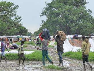 Men carrying their belongings on their heads arrive in South Sudan after fleeing violence in Sudan.