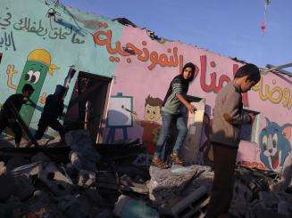 Children walk through the wreckage of a school in Gaza on November 24